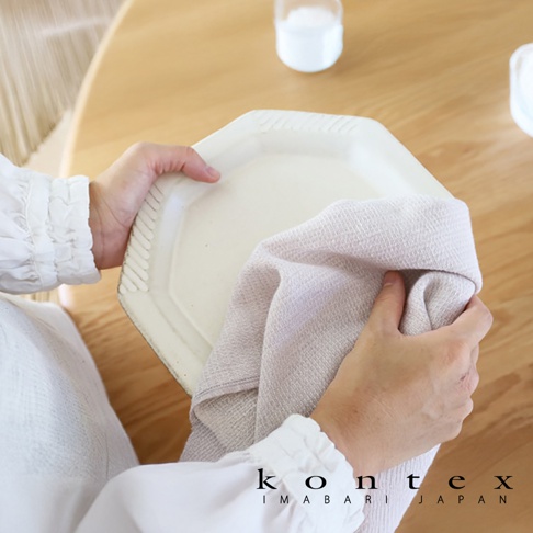 MOKU Organic 有機棉長毛巾，淺米色，織有細緻紋理，用於擦拭白色盤子。