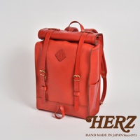 一咖鮮紅色皮革製成的後背包，具有捲口設計、兩條可調節肩帶、側邊口袋，並以金屬扣環固定。