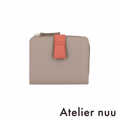 這是一款 Atelier nuu 品牌的 noble 系列皮革短夾，整體為淺灰褐色皮革材質，設計為雙折結構並配有 L 型拉鍊，正中央裝飾有一個顯眼的珊瑚橘色皮革按扣飾帶，整體呈現極簡且優雅的風格。