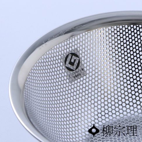 柳宗理不鏽鋼瀝水盆局部特寫，邊緣刻有 18-8 Martian 與 Made in Japan 字樣，盆身佈滿均勻細緻的濾孔，並貼有 Good Design Award 優良設計獎貼紙，下方印有柳宗理品牌名稱。