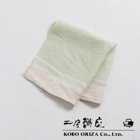 一塊淺綠色的純亞麻斜紋廚房拭巾，帶有米白色滾邊和細條紋，質地柔軟，適合各種用途。