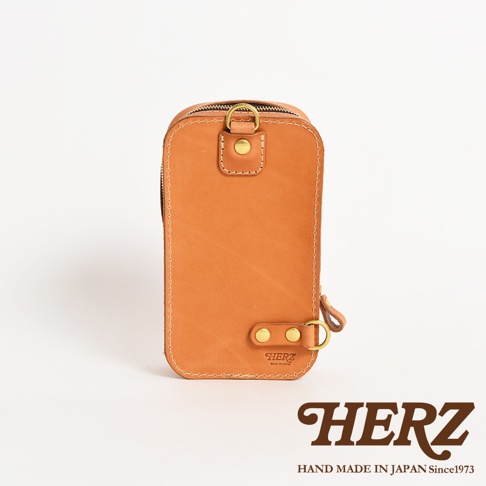 日本HERZ 職人手作皮革兩用直立型斜背包，淺棕色皮革材質，正面有品牌標誌，並以車縫線和金屬釦件裝飾。