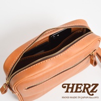 棕色皮革手提包，拉鍊打開，內部可見手機和卡片，飾有白色縫線。