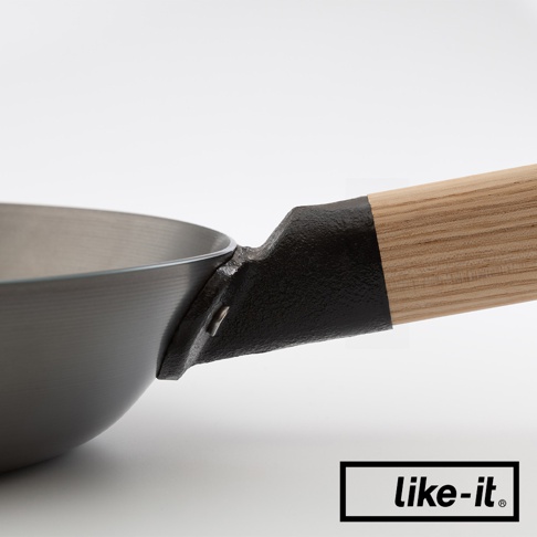 特寫直火專用萬能調理鐵鍋的鍋柄連接處，鍋身為金屬材質，鍋柄為木質，連接處為黑色金屬。