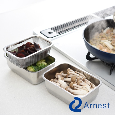 Arnest 不鏽鋼多功能濾網保鮮盒3件組，包含盛裝食材的濾網和不鏽鋼調理盤，旁邊是裝有香菇的不鏽鋼保鮮盒，後方有正在烹調的鍋子。