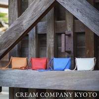 四款皮革隨身側背包，顏色分別為橘色、紅色、藍色及白色，皆配有同色系長背帶。