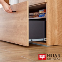 淺棕色木紋抽屜櫃，抽屜拉開露出內部收納盒，展示櫃腳下方有防倒固定墊。