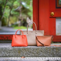 三款皮革手提包，分別為亮橘色、卡其色和棕色。亮橘色手提包造型簡約，配有提把。卡其色托特包較大，同樣有提把。棕色斜背包配有可調式斜背帶。