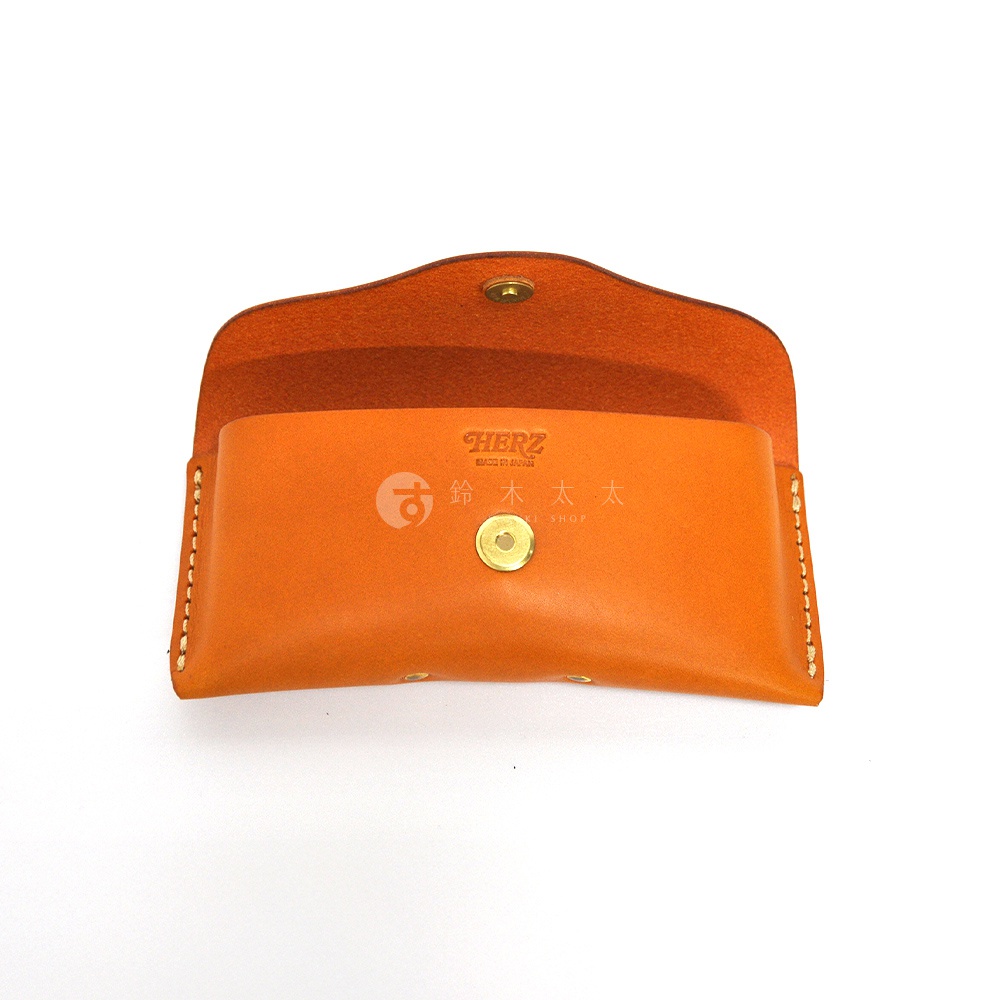 橘色皮革眼鏡收納盒，附有金色按扣，內襯橘色絨布，盒蓋處印有品牌標誌。