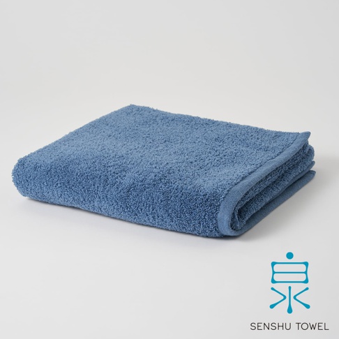 藍色長纖迷你浴巾，觸感柔軟，質感蓬鬆，邊緣有精緻的包邊設計，整體呈摺疊狀，背景為純白色。