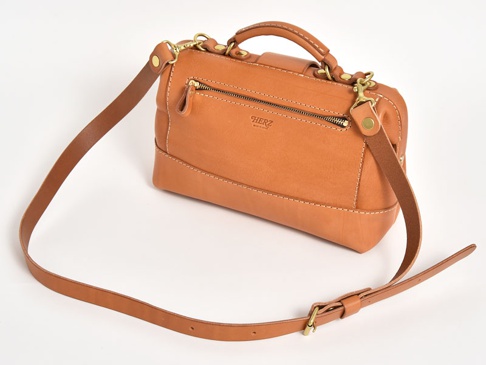職人手作皮革兩用迷你口金單肩包，採用天然棕色皮革製成，配有金色金屬配件和可拆卸肩帶。包身線條簡潔，縫線清晰，正面有一個拉鍊口袋。