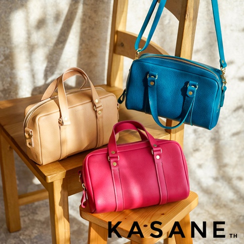 三個不同顏色的 KASANE 職人手作迷你波士頓包擺放在木製椅子上，包含裸色、亮粉色與懸掛著的藍色皮革包款，展現皮革細膩質感與簡約設計。