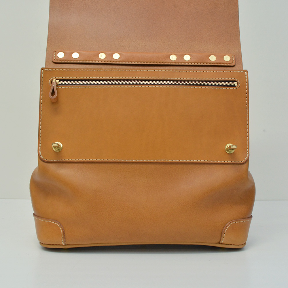 職人手作皮革旅行商務兩用波士頓包，採用棕褐色皮革，設有金色拉鍊外袋，袋蓋以金色卯釘裝飾，並有金色旋鎖扣，整體風格簡潔而精緻。