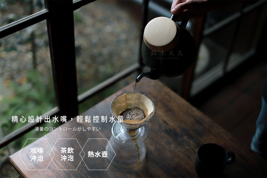 黑色琺瑯手沖壺，搭配木質壺蓋，正緩慢傾倒熱水至咖啡濾杯中，展現細緻的注水控制。