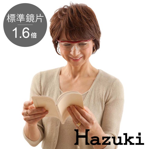 一位女性戴著亮紅色鏡框的葉月抗藍光放大鏡，正在閱讀一本小書。鏡片為標準鏡片，放大倍率為 1.6 倍。