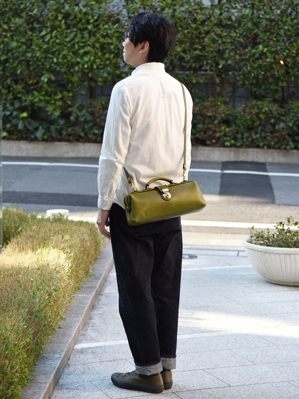 綠色皮革製橫長形單肩包，配有頂部提把和可拆卸肩帶，包身中央有金色鎖扣。