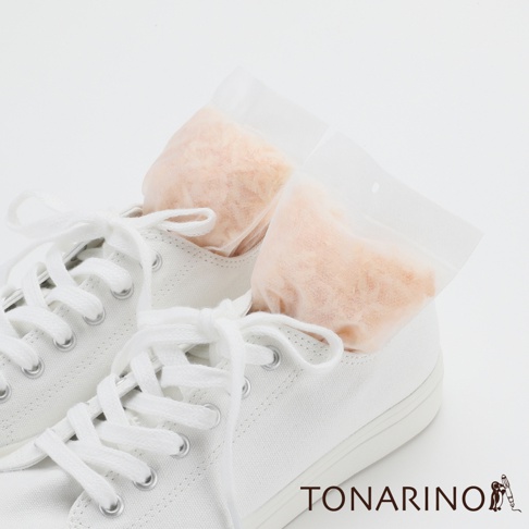 一雙白色帆布鞋，鞋內各放入一個透明小包裝的檜木屑除濕消臭包，包內為淺橘色顆粒狀材質。