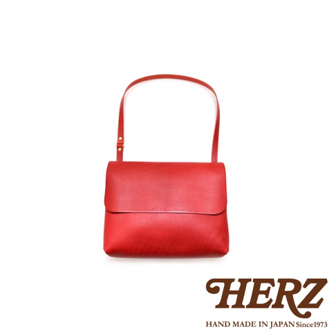 紅色職人手作皮革經典郵差包，以簡潔方正的包身設計，搭配可調節長度的單肩背帶，展現皮革的自然紋理與質感。