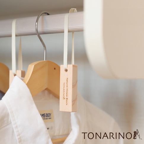懸掛在衣櫃內的天然檜木條，木質呈現淺棕色，帶有細緻的紋理，並以白色細繩懸掛。