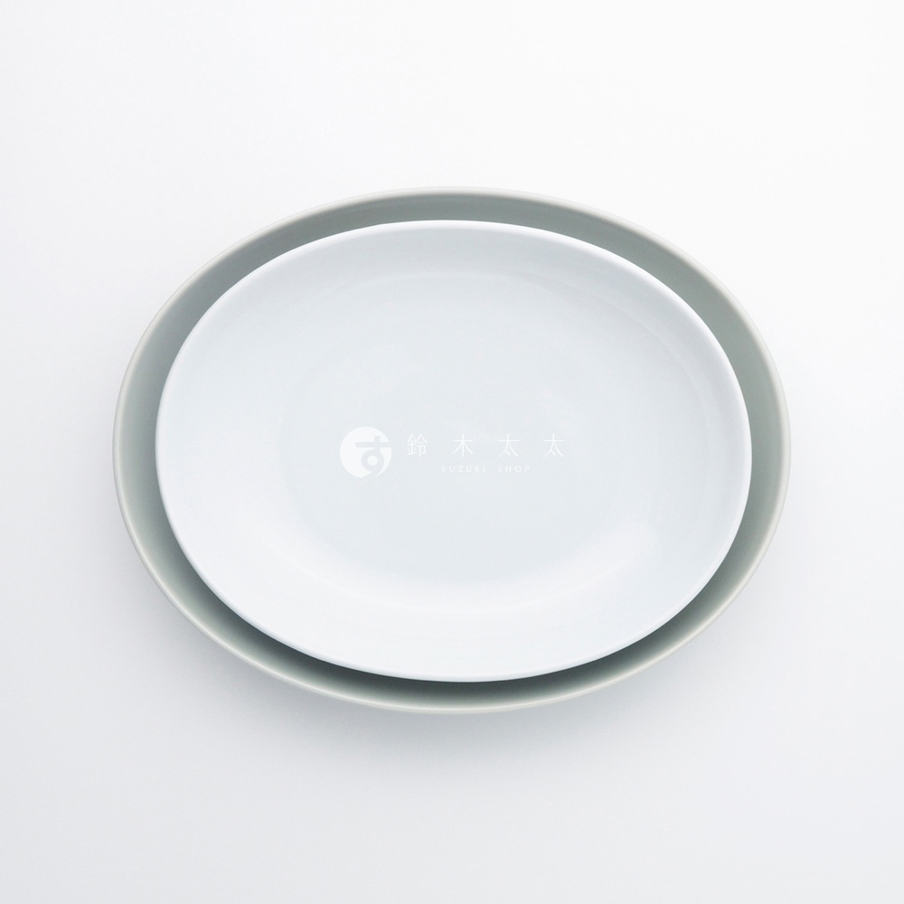 兩個波佐見燒 Common 陶瓷橢圓餐盤，一個為純白色，另一個為淺灰色，均為 27 公分尺寸，呈現疊放的俯視角度。