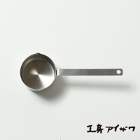 一個不鏽鋼製的長柄計量杯，杯口帶有兩個小傾倒口，杯身為圓柱形，手柄扁平且末端有掛孔。