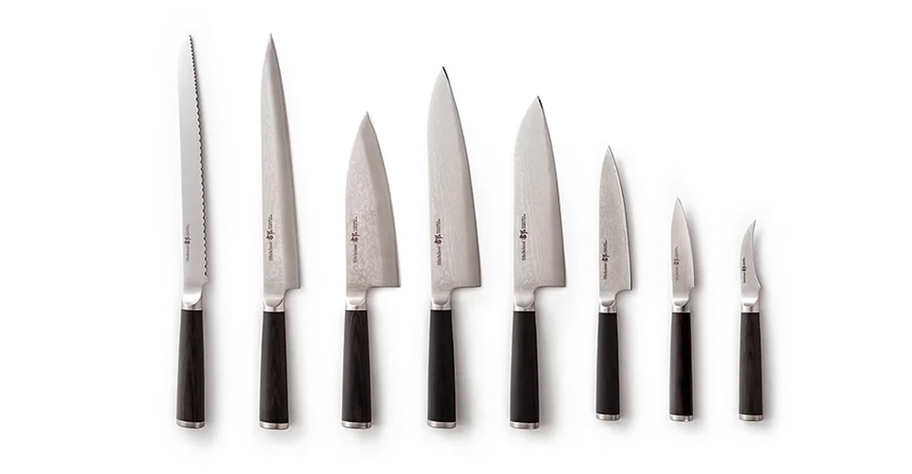 一排共八把不同尺寸的志津匠廚刀，從左至右依序為麵包刀、主廚刀、三德刀、日式廚師刀、utility knife、削皮刀、以及兩把小刀。