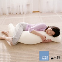 一名女性抱著一個米白色長條形抱枕，側臥在地毯上。抱枕呈彎曲狀，方便身體倚靠。