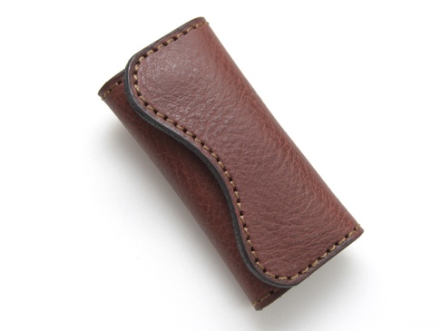 職人手作皮革鑰匙包，採用棕色皮革，表面有細緻紋理，搭配米色縫線，設計簡潔，可收納鑰匙。