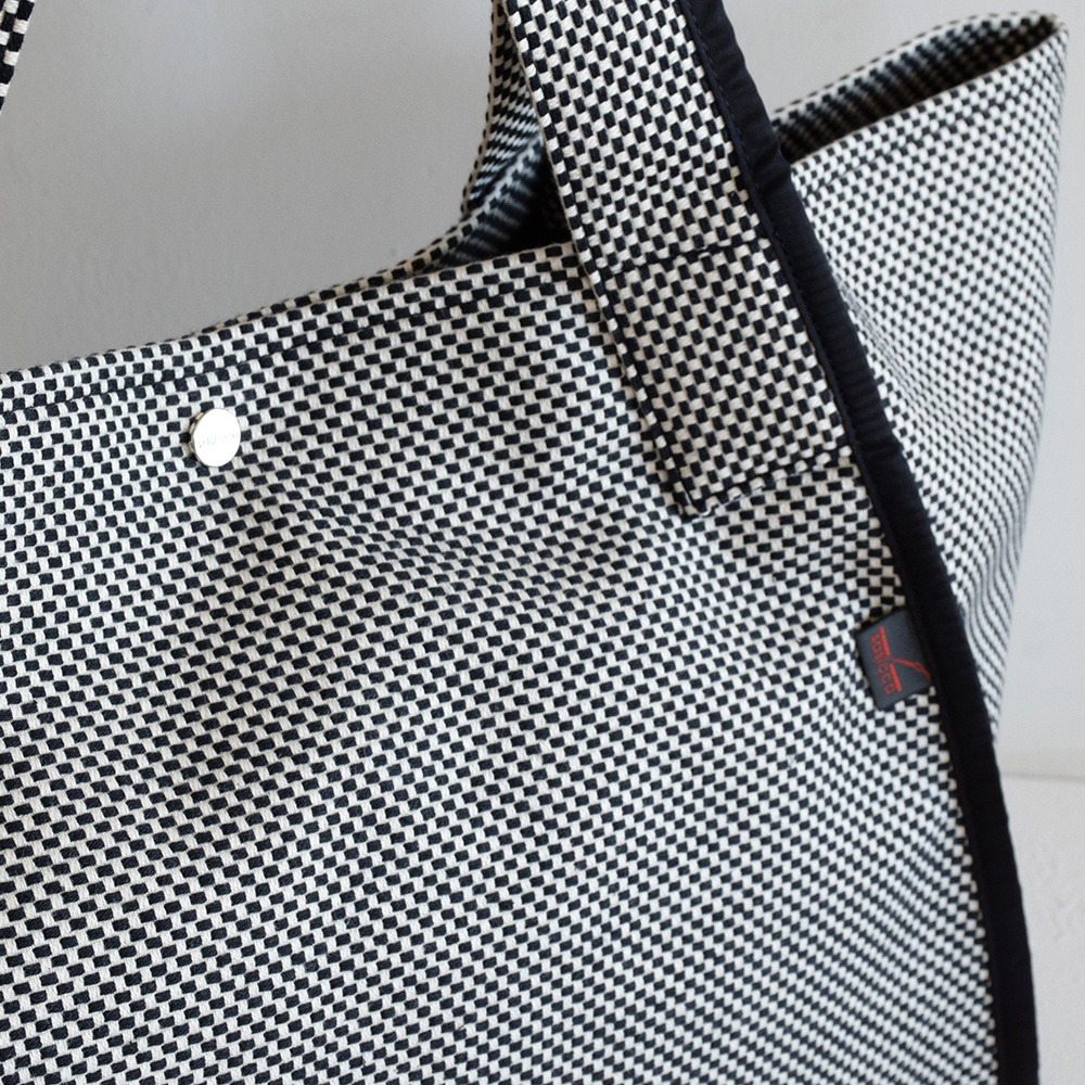 黑白格紋三河木綿刺子織材質托特包，配有銀色壓扣和黑色滾邊，左側有紅色品牌標籤。
