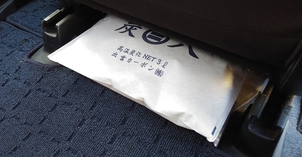 炭質除濕包放在汽車座椅下方，包裝上有日文文字。
