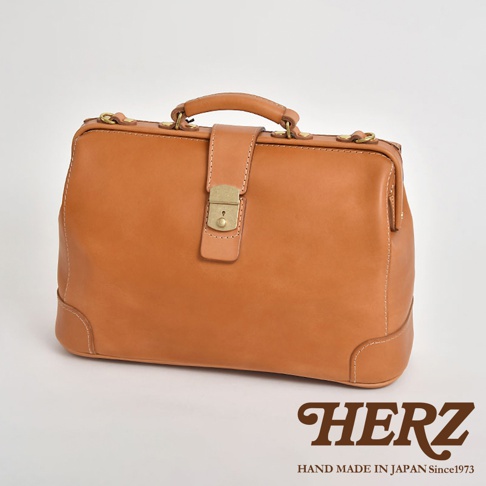 職人手作皮革商務旅行兩用公事包，淺棕色皮革，附有黃銅色鎖扣和提把，設計簡潔經典，適合商務及旅行場合。