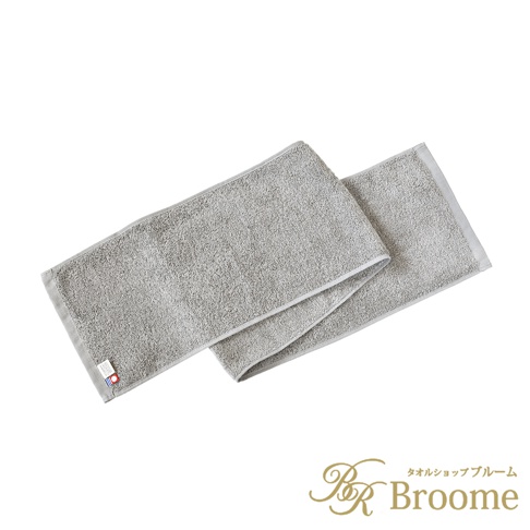 一條淺灰色長毛巾，材質柔軟，邊緣有精緻的織邊。毛巾表面有細緻的毛圈，觸感良好。