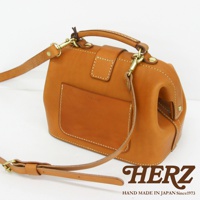 職人手作皮革方型迷你醫生包，採用原色皮革材質，配有可調式肩帶和頂部提把，側邊設有貼袋，整體風格簡約經典。