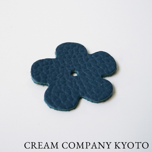 深藍色皮革製成、花朵形狀的吊飾，帶有細緻的紋路和一個小孔，適用於京都職人手作肩背手提托特包。