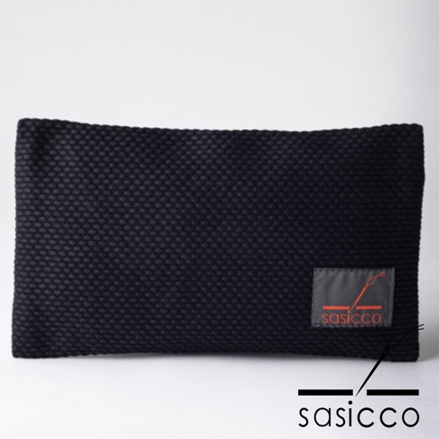 黑色三河木綿刺子織文件收納包，表面有細小的織紋，左下角有灰色標籤，標籤上有紅色縫線圖案和「sasicco」品牌字樣。