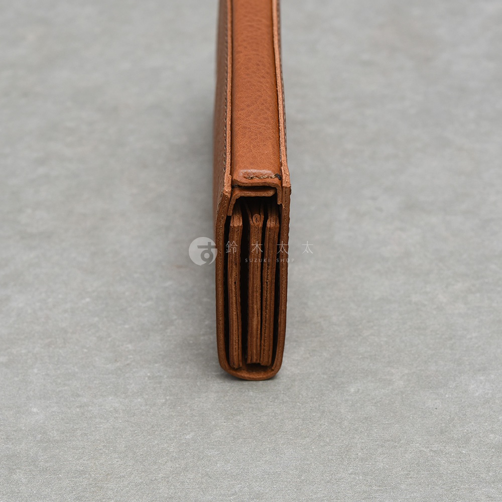 側面拍攝日本HERZ職人手作皮革Organ磁扣長夾，展現其豐富層次的風琴式內部結構，皮革呈現自然的深棕色紋理，整體設計簡約穩重，中間印有鈴木太太字樣。