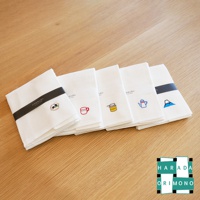 五條白色八重紗萬用擦拭巾，分別繡有壽司、咖啡杯、果醬罐、茶壺和富士山圖案，以黑色和白色束帶固定。