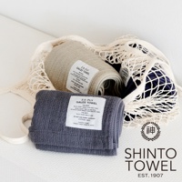 灰色、米白色和深藍色的2.5層紗浴巾，部分置於網狀收納袋中，展示其柔軟的材質與精緻的織紋。