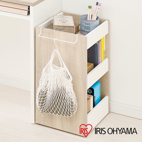 木質可移動置物櫃，淺木紋飾面，搭配白色邊框，設有三個開放式層架，左側掛有白色網狀購物袋。