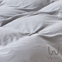 柔和的灰色床單，呈現出自然褶皺的紋理，右下方可見「Wasaraf」品牌標誌。