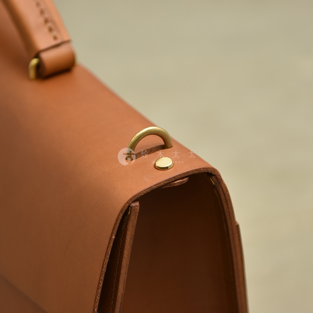 職人手作皮革Organ兩用商務公事包 G-93，採用光滑的淺棕色皮革，配有黃銅色金屬扣環和鉚釘，展現簡約經典的設計。