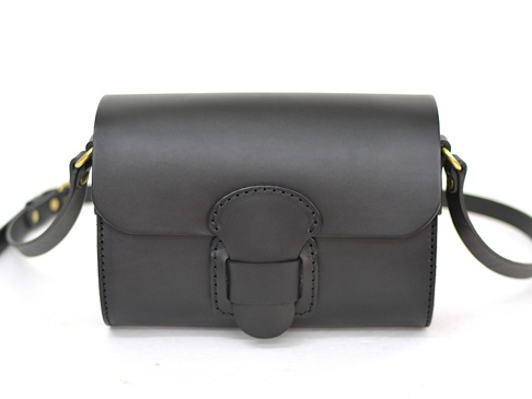 黑色皮革寬扣帶馬鞍包，配有金色金屬配件，簡約設計，適合日常搭配。