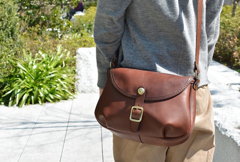 職人手作皮革休閒旅行馬鞍包 (CK-20)，深棕色皮革，翻蓋設計，配有黃銅扣環及皮帶，斜挎於肩上。