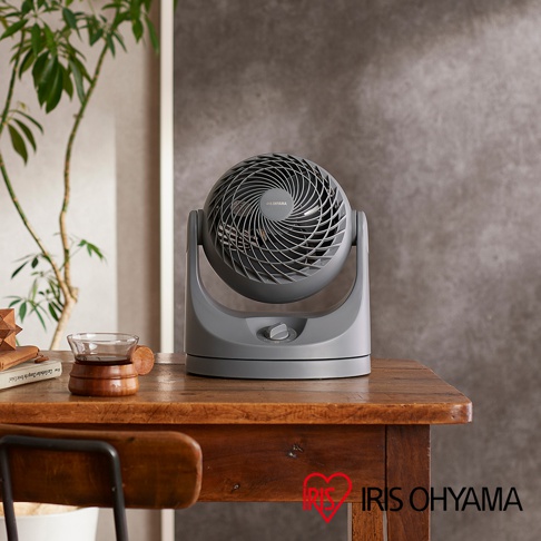 PCF-MKM15 空氣循環扇，灰色塑膠機身，帶有可調節角度的圓形風扇頭，前面板有品牌標誌和旋鈕開關，放置於木桌上。