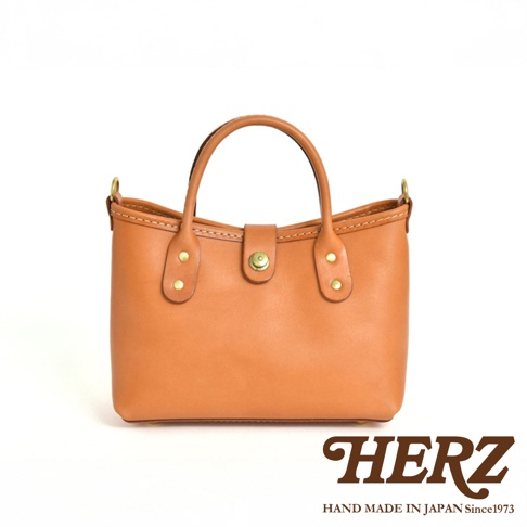 職人手作皮革迷你托特包 T-11，採用光滑棕褐色皮革製成，配有圓形提把、頂部磁扣和金色五金配件。