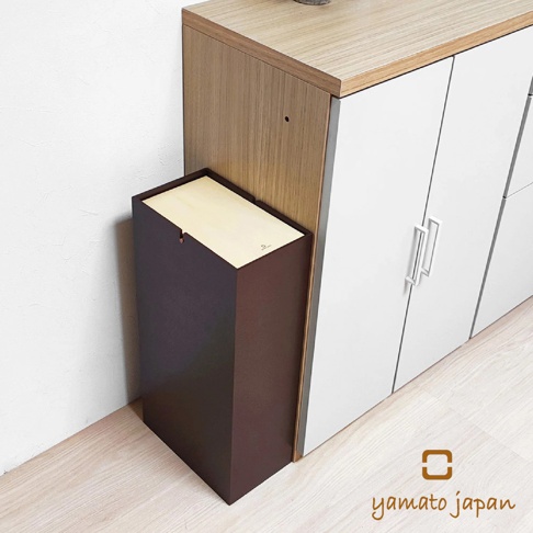 深棕色方形擺動式垃圾桶，搭配淺木色頂蓋，置於白色櫥櫃旁，展示其簡約的木質風格設計。