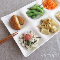 白色陶瓷六格小菜盤，盛有炸物、毛豆、切絲胡蘿蔔、竹筍、飯糰及漬物。