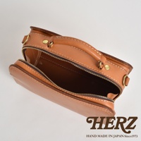 棕色皮革兩用方形單肩包，帶有拉鍊開合、提把和金屬扣件，展現職人手作質感。