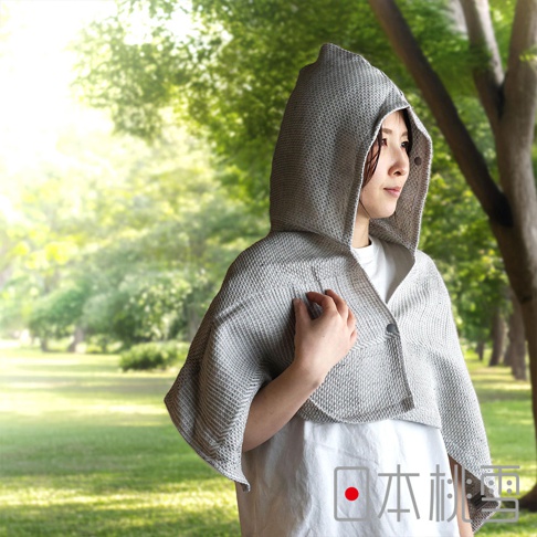 身穿日本桃雪SEK抗菌防臭檜木鬆餅紋連帽浴巾的女性，於陽光灑落的公園中，微微側頭望向遠方。