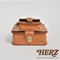 職人手作皮革立體口袋兩用單肩包，呈現自然棕色皮革，帶有精緻縫線與金屬鎖扣，造型簡潔，適合日常搭配。